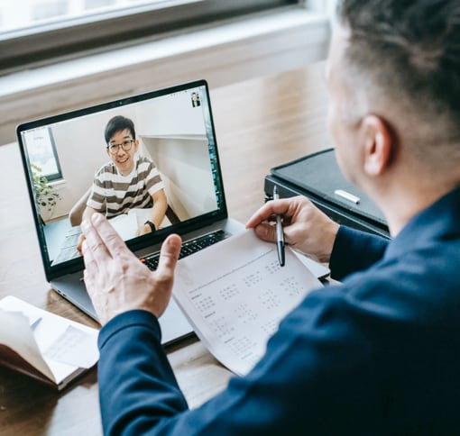 a man in a videocall with another man on the screen in front of him