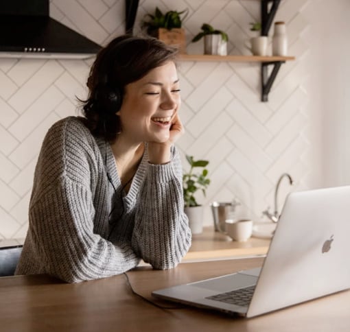 a woman in a videocall with her laptop on a table in front of her